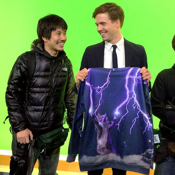 Översättaren Takako Makino (t.v.) tillsammans med SVT:s meteorolog Nils Holmqvist och hans världskända tröja. Reportern Shohei Umemura och fotografen Mutsuaki Kiyohara från TV Tokyo tog sig till SVT-huset just på grund av den klassiska kattröjan.