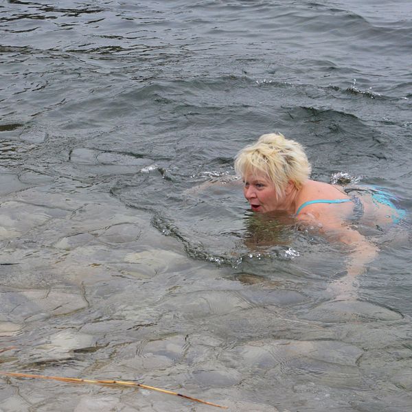 Carina Fransson tar sig ett vinterbad i Vättern. Hon är ute på öppet vatten, men mindre isflak syns i nederkanten av bilden.