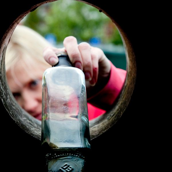 En kvinna lägger i en glasflaska i en glasigloo.