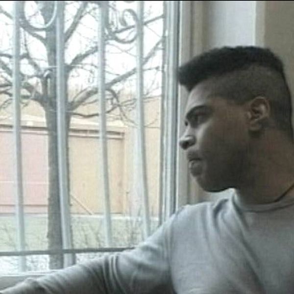en man tittar ut genom fönster med galler