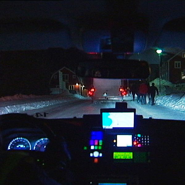 Bild inifrån polisbil ut på snöig väg med trafik och människor.