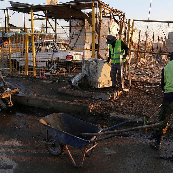 Kommunalarbetare städar upp efter bombdådet i Bagdad i dag.