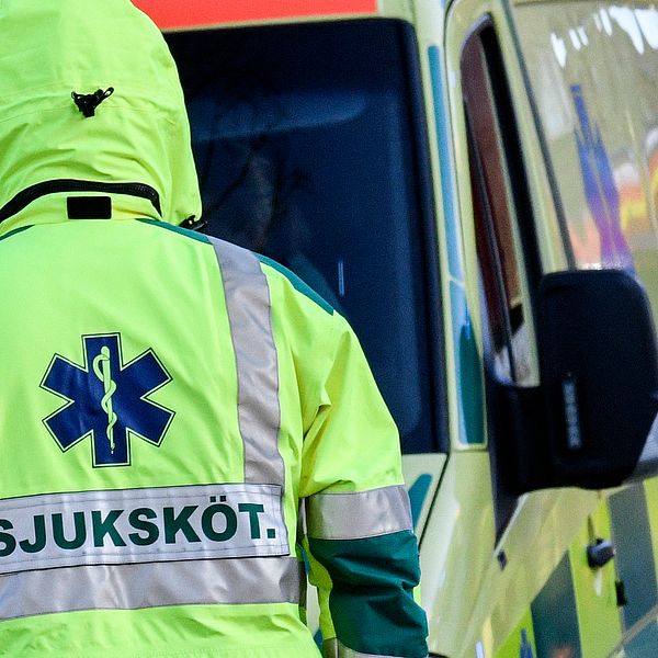 En ambulanspersonal som står med ryggen mot kameran. Arkivbild