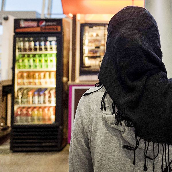 En kvinna med hijab framför ett kafé.