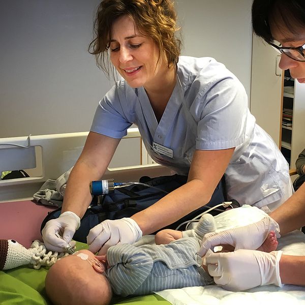 Två specialistsköterskor tar hand om ett nyfött barn