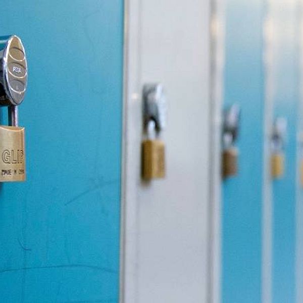En elev går i en skolkorridor med blåa skåp