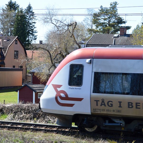 Passageratåg passerar framför villor.