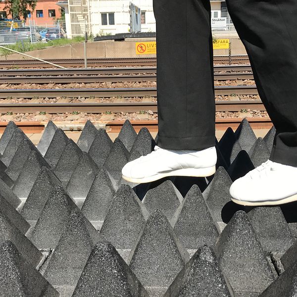 fötter går på pyramidformade gummimattor vid järnvägsspår