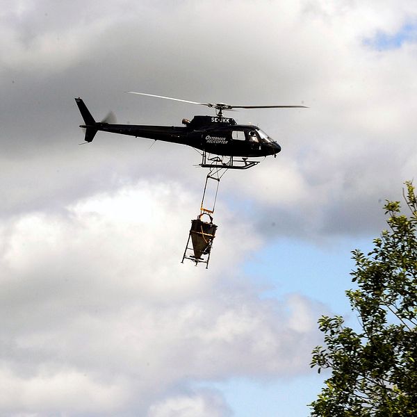 en helikopter flyger med behållare hängande under