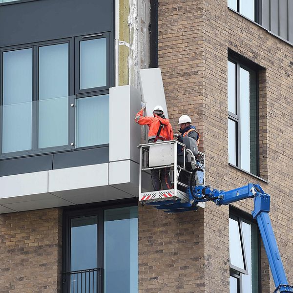 Arbetare plockar bort fasadmaterial från en byggnad i Wythenshawe i Manchester.