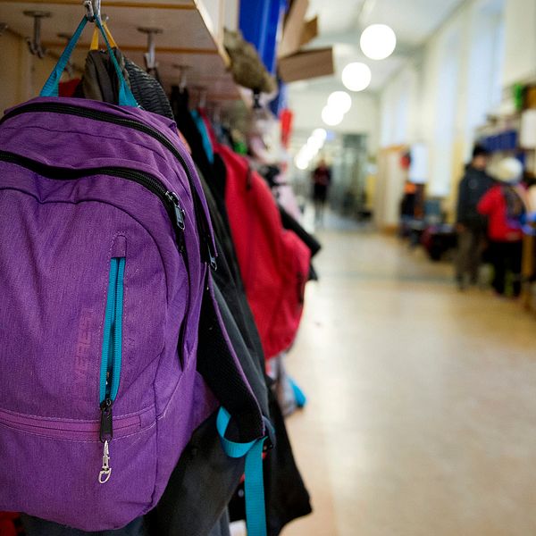 Korridor i en skola, väskor och kläder som hänger på klädhängare.