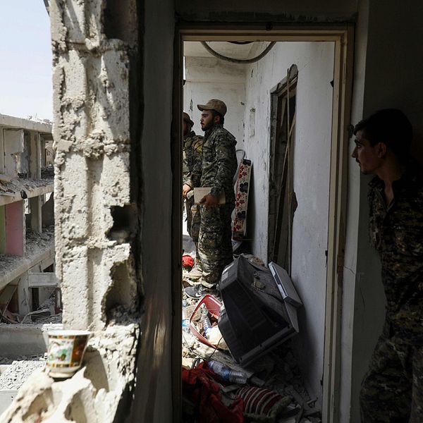 Stridande medlemmar av YPG och SDF genomsöker förstörda byggnader i Raqqa, Syrien.