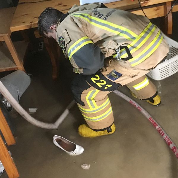 Brandman pumpar ut vatten ur källare.