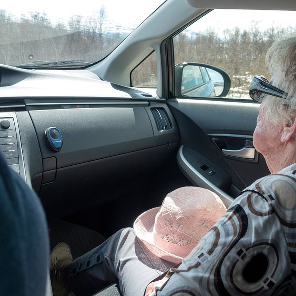 Äldre kvinna sitter i passagerarsätet i en bil.