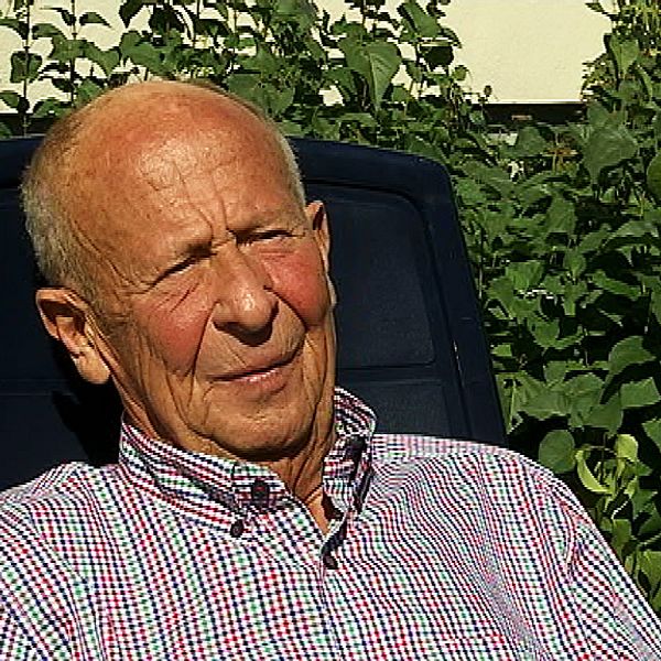 Arne Carlsson, en man, sitter i rutig skjorta ute i solen och tittar snett bredvid kameran.