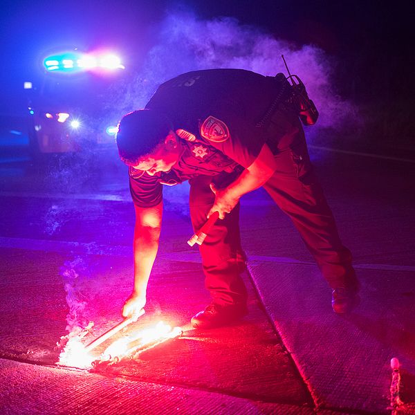 En polis lägger ner säkerhetsbloss för att blockera vägen till Arkema kemikalieanläggning utanför Houston