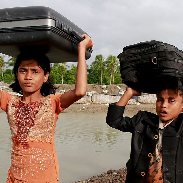 Två rohingyabarn på flykt bär sina tillhörigheter i Teknak, Bangladesh.
