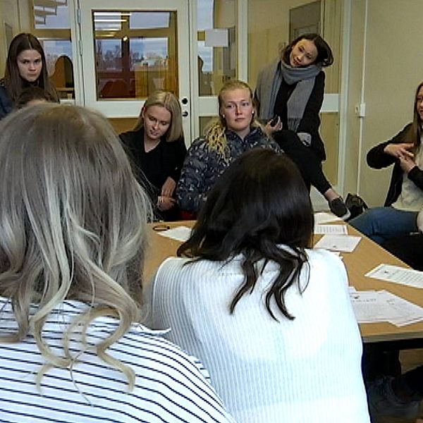 Gymnasieelever, alla tjejer, sitter runt ett bord och pratar med varandra.