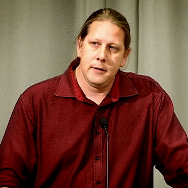 Patrik Liljeglöd (V) står i en talarstol och talar i en mick.