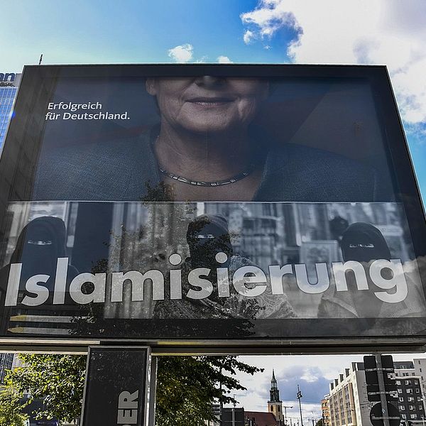 En valaffisch som visar en halv Angela Merkel och ordet islamisering.