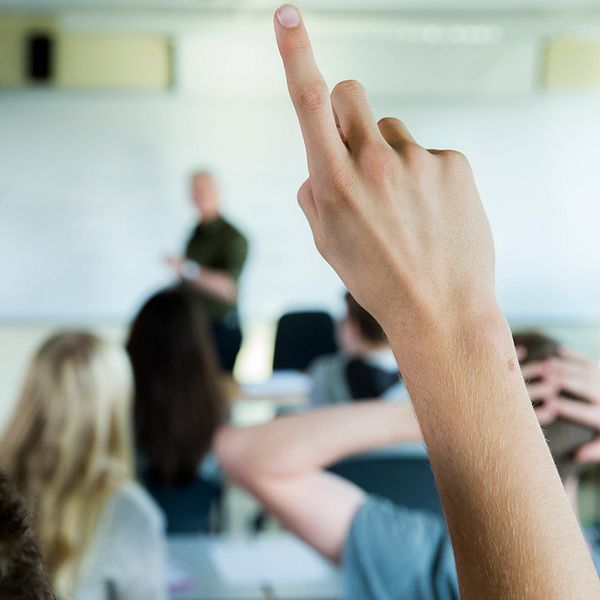 En elev räcker upp handen i ett klassrum