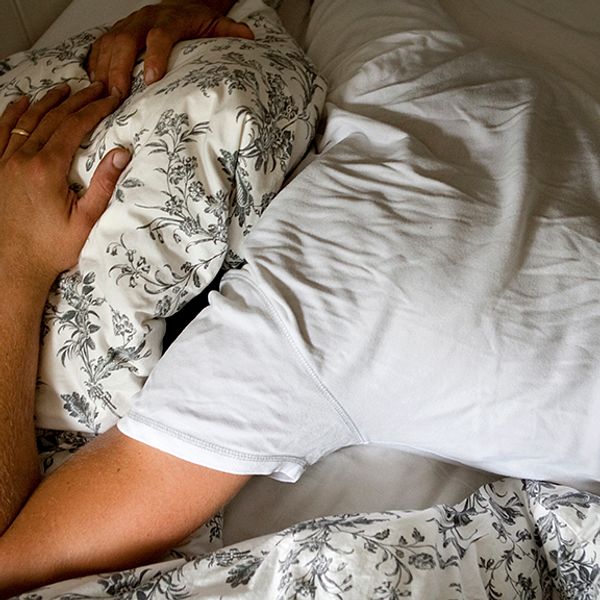 okänd med sömnproblem trycker kudde över huvudet