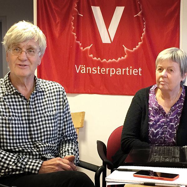 Lars Bjurström och Carina Flodman Andersson sitter framför en vänsterparti-flagga.