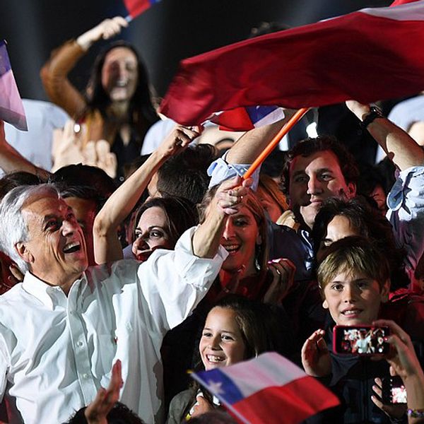 Sebastian Piñera står och vajar en stor chilensk flagga i publikhav.