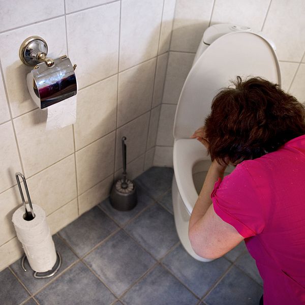 En kvinna hänger över en toalettstol.