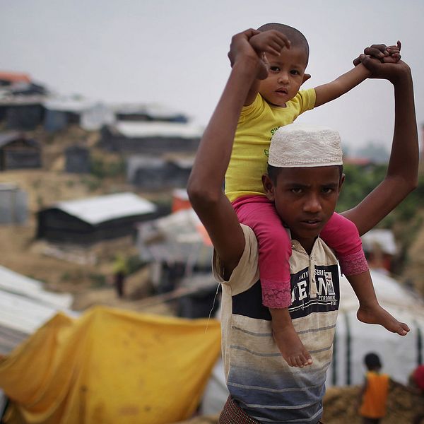En rohingya pojke bär ett barn på sina axlar i flyktinglägret Jamtoli i Bangladesh.