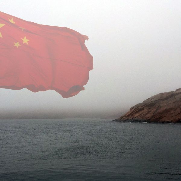 Dimmig bild av kusten intill en kinesisk flagga