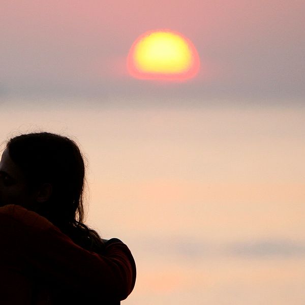 Siluetter av par som kysser varandra med solnedgång i bakgrunden.