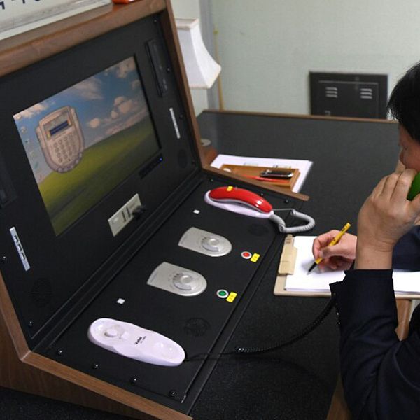 En sydkoreansk tjänsteman sitter vid en skärm och pratar i telefon.