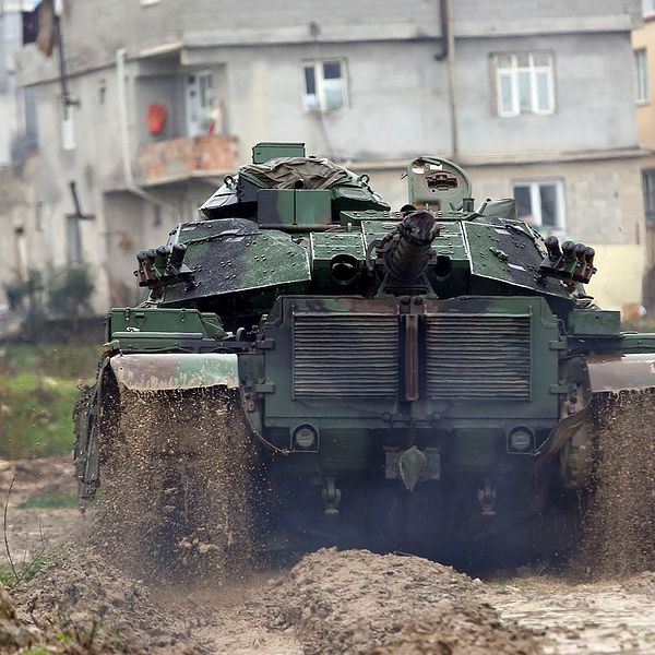 En grön turkisk stridsvagn som åker nedför en lerväg.