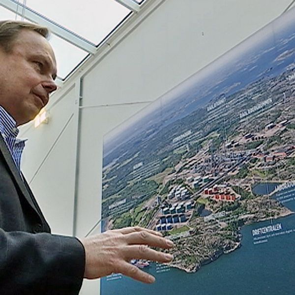 Peter Abrahamsson intill flygbild av preemraffs anläggning i Lysekil.