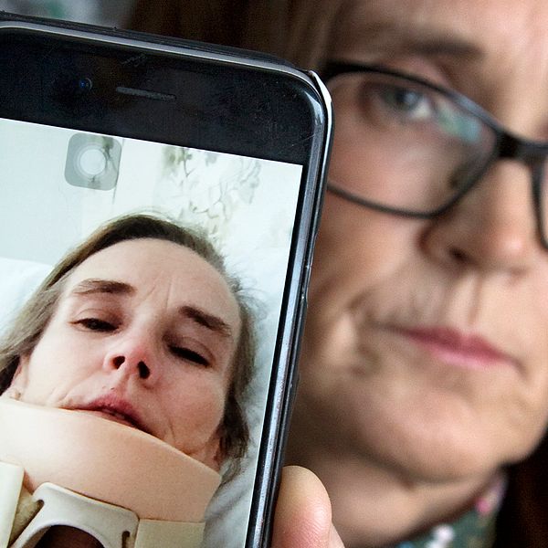 medelålders kvinna håller fram mobil för att visa bild på sig själv med nackkrage