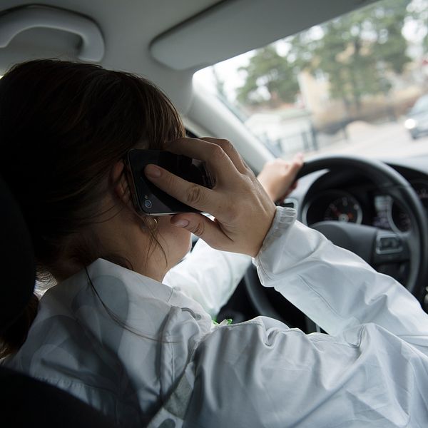 Kvinna talar i mobiltelefon i bil.