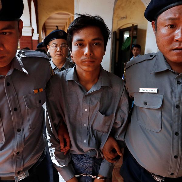 Kyaw Soe Oo har handfängsel på sig och går mellan två poliser som håller i hans armar.