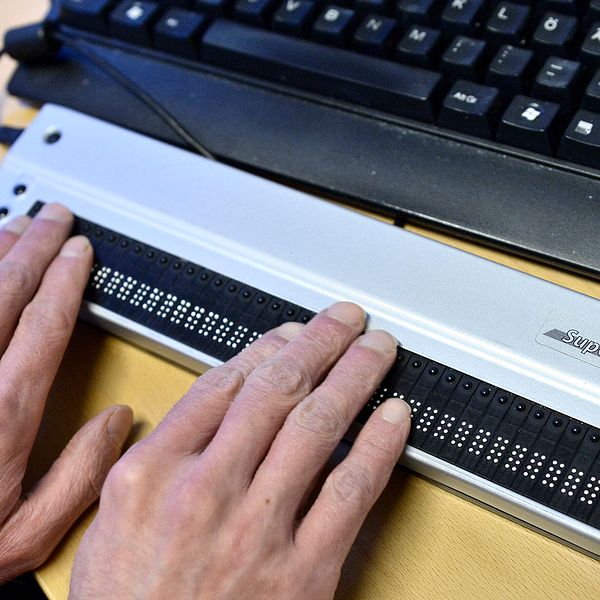 En synskadad man skriver på sin skärmläsare till sin dator.
