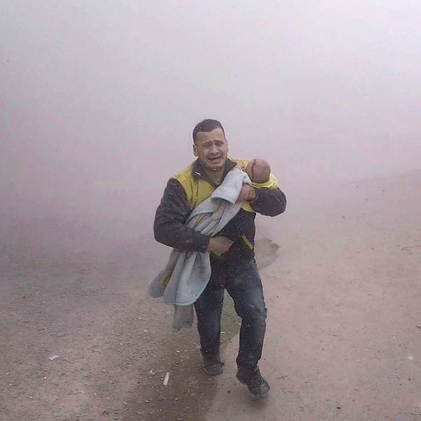 En man tillhörande Vita hjälmarna bär sin skadade son när han flyr från ett flyganfall på tisdagen.