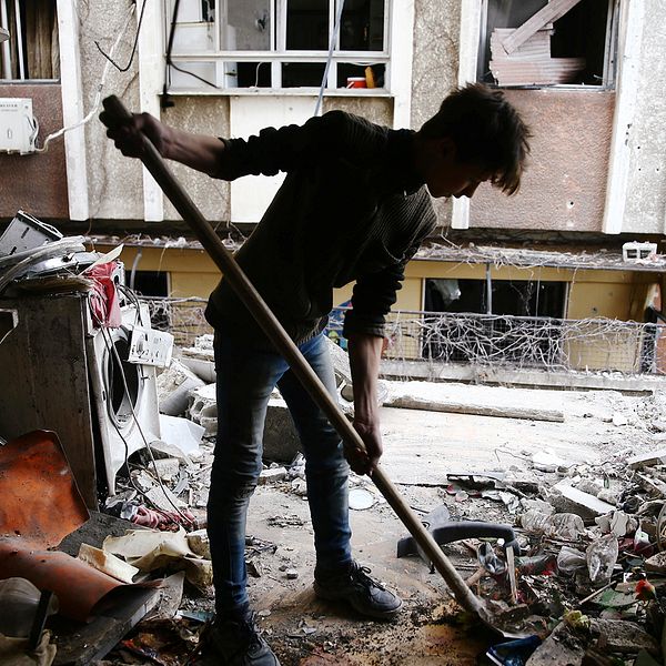 En ung man städar vid ett hus som skadats i under söndagens flygattack över östra Ghouta i Syrien.