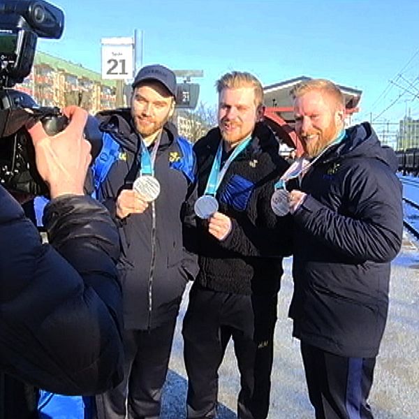 Oskar Eriksson, Rasmus Wranå och Niklas Edin visar upp sina medaljer för en kamera