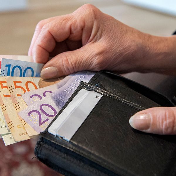 En kvinna håller i en plånbok med sedlar.