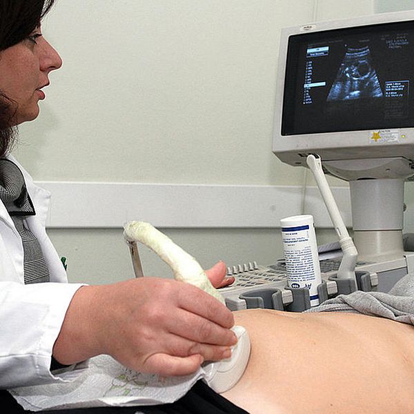 Läkare som genomför ett ultraljud på en kvinnlig patient.