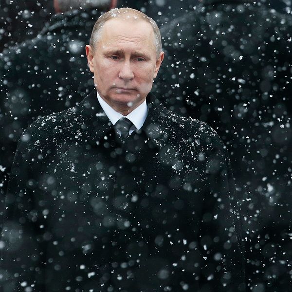 Ryska presidenten Vladimir Putin står klädd i svart i ett snöfall.