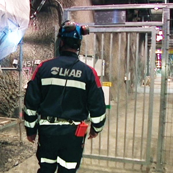 En man i arbetskläder står utanför en grind nere i en gruva.