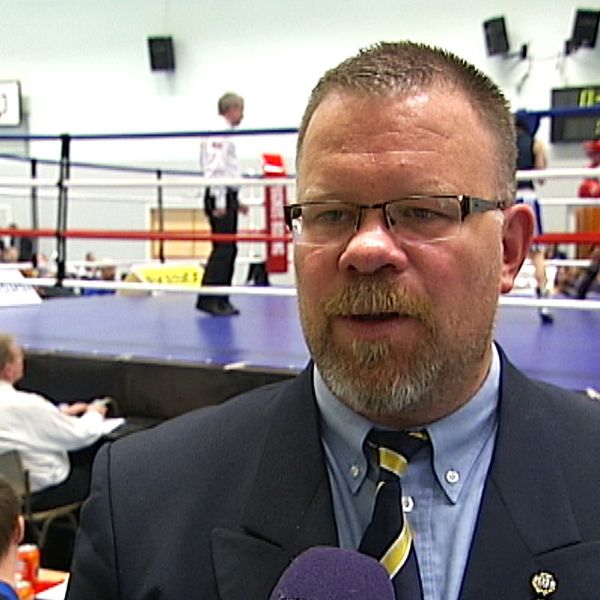 Anders Holmberg tittar snett förbi kamerab, i bakgrunden syns en boxningsring