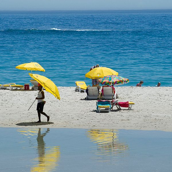 Solbad på stranden vid Camps bay i Sydafrika.