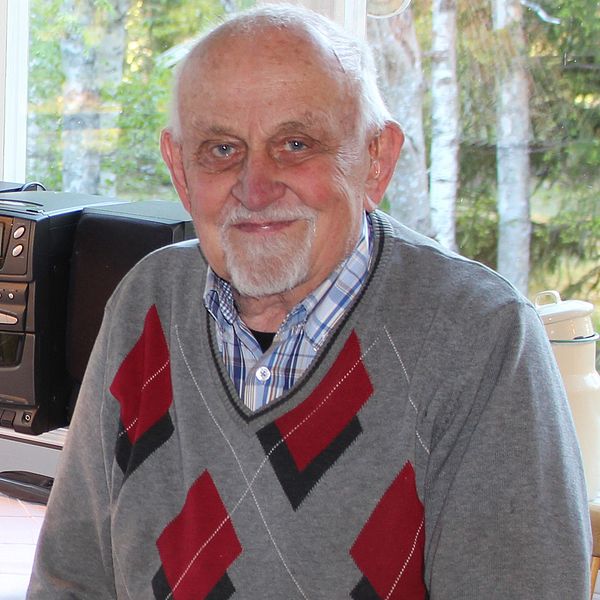Bild på Jöran Lundberg, som sitter framför en stereo i hemmamiljö med en kaffekopp bredvid sig.