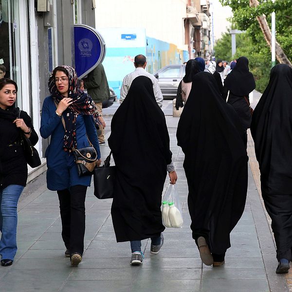 Fem kvinnor går på gatan i Teheran, Iran. Två har slöja, tre har den traditionella chadoren.